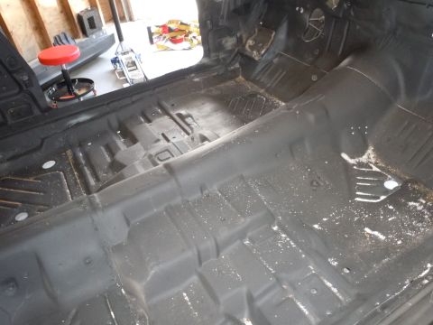 2001 Ford Crown Victoria - The interior floor of a vehicle has been stripped and coated, showing a bare metal structure with scattered debris.