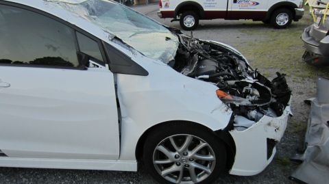 2012 Mazda Mazda 5 - White 2012 Mazda Mazda 5 with severe front-end collision damage. Other vehicles are present.
