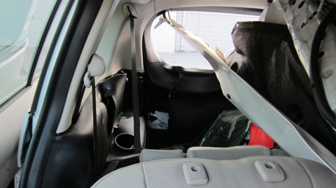 2012 Mazda Mazda 5 - The rear interior of a damaged vehicle shows significant damage to the cargo area and upholstery.