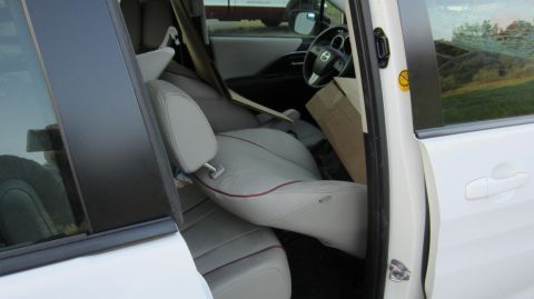 2012 Mazda Mazda 5 - The interior of a white minivan shows folded seats and a cardboard box, with a glimpse of the steering wheel.