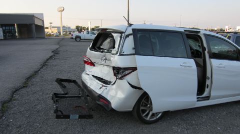 2012 Mazda Mazda 5 - This minivan has significant damage to its rear end and a trailer hitch attachment is visible on the ground.