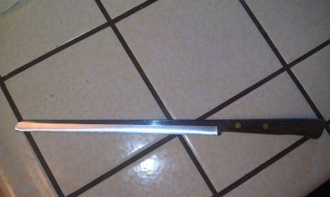 1989 Ford Bronco - A bread knife with a serrated blade and a wooden handle rests on a tiled surface.