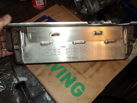 2004 Mercury Grand Marquis - A metal oil pan with visible Ford and Garrett part numbers is held for inspection.