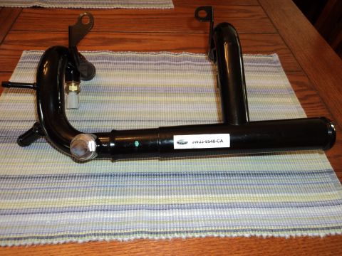 2004 Mercury Grand Marquis - A black metal automotive coolant pipe, identified by a part number, is displayed on a table.
