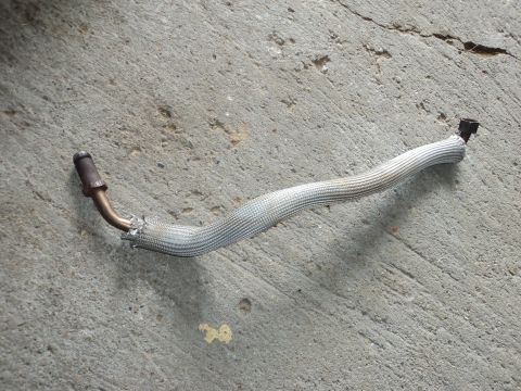 2004 Mercury Grand Marquis - A detached exhaust pipe with a protective heat shield lies on a concrete surface.
