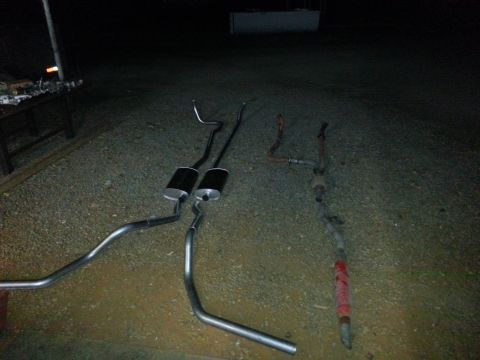 1978 Ford Bronco - Two exhaust systems, one new and one old, are displayed on the ground, likely for a vehicle repair or upgrade.