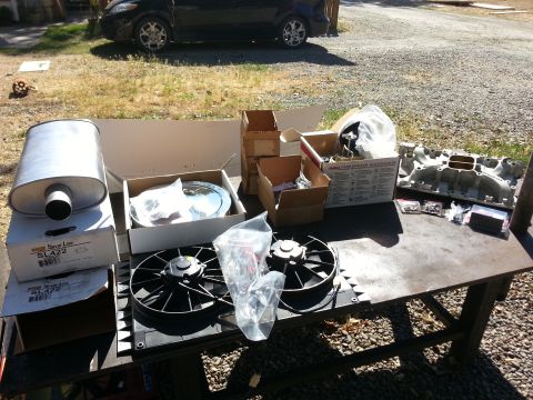 1978 Ford Bronco - Various engine and exhaust parts are organized on a workbench, ready for a motor rebuild.