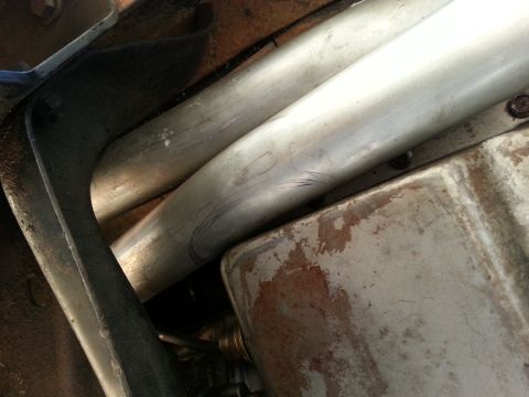 1978 Ford Bronco - Underneath view of exhaust pipes and oil pan, showing signs of wear and rust.