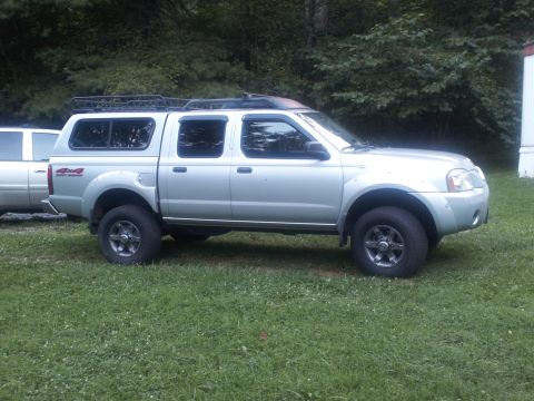 2003 Nissan Frontier - This silver 2003 Nissan Frontier pickup truck is equipped with a cap and roof rack, seen from the side.