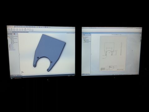 1967 Ford F-100 - Photograph of dual monitors showing a SolidWorks bracket model alongside its dimensioned engineering drawing.