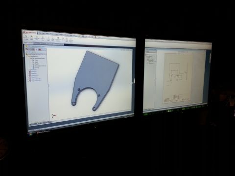 1967 Ford F-100 - Photograph of dual monitors showing a SolidWorks bracket model alongside its dimensioned engineering drawing.