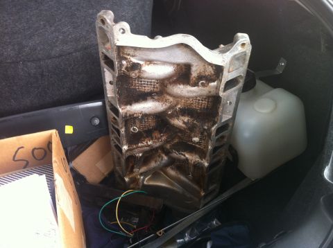 2003 Ford Crown Victoria - Engine intake manifold with visible carbon buildup, stored with other car parts.