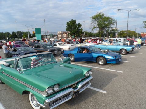 1971 Ford Ranchero - A variety of classic cars are parked in a lot under a cloudy sky.