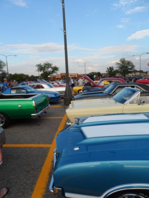 1971 Ford Ranchero - A green 1968 Ford Ranchero is parked in a lot with other classic cars under a cloudy sky.