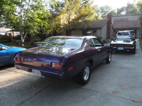 1971 Ford Ranchero - A purple 1973 Dodge Dart Sport is parked in a driveway with two other vehicles visible.