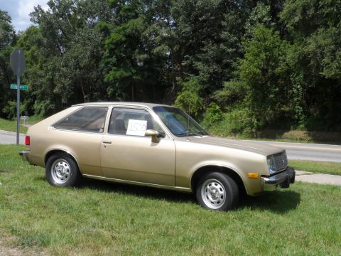 1971 Ford Ranchero - Gold hatchback car with a price tag in the window sits on a grassy shoulder next to a road.