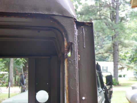 1978 Ford Bronco - Close-up of a heavily rusted door frame, with another vehicle partially visible behind it.