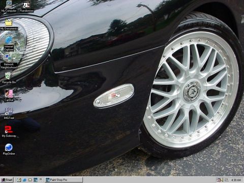 1999 Ford Taurus - A close-up view of a black car's front corner, highlighting its wheel and fender, with a computer desktop reflected on its surface.