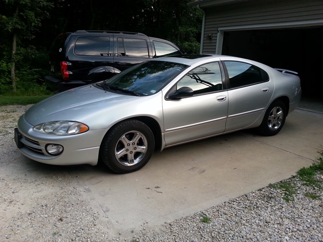 Silver sedan with sunroof, 3q-front view. A black SUV is behind it