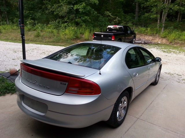 Silver sedan parked on concrete driveway, black pickup truck in background