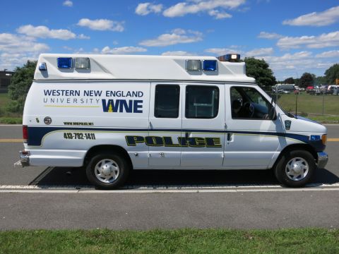 2001 Ford Crown Victoria - A white police van for Western New England University WNE is seen from the side, displaying "POLICE" text and emergency lights.