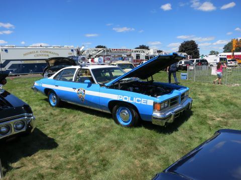 2001 Ford Crown Victoria - A vintage police car, possibly a Pontiac, is displayed with its hood open at an outdoor event.