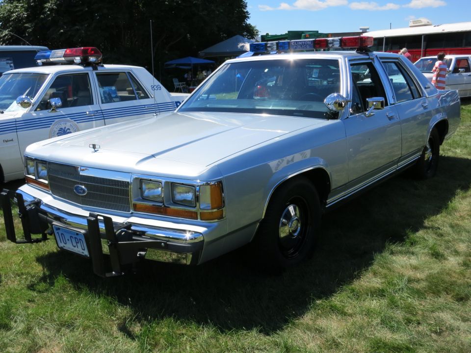 Silver police car with push bumper and light bar. Another police car is visible to the left