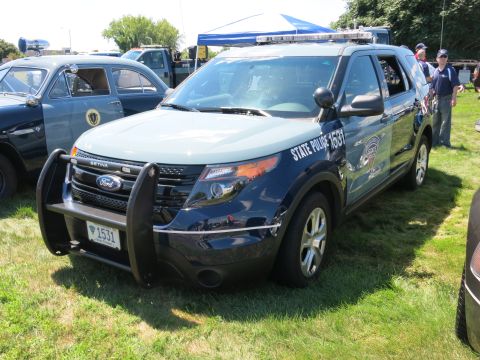 2001 Ford Crown Victoria - A dark blue and light blue police SUV is parked on the grass, with a push bar and emergency lights.