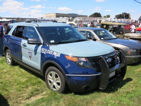 2001 Ford Crown Victoria - A police SUV is parked on grass with other vehicles and emergency vehicles in the background.