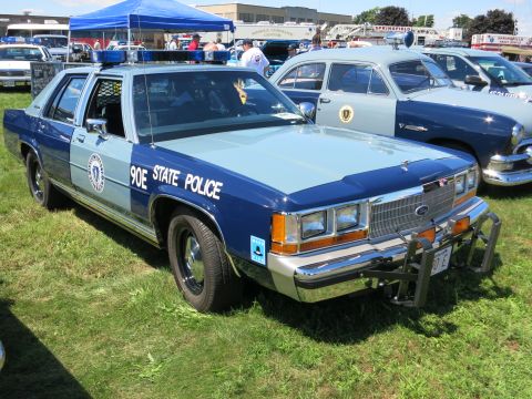 2001 Ford Crown Victoria - Massachusetts State Police car parked on grass with other vehicles in the background.