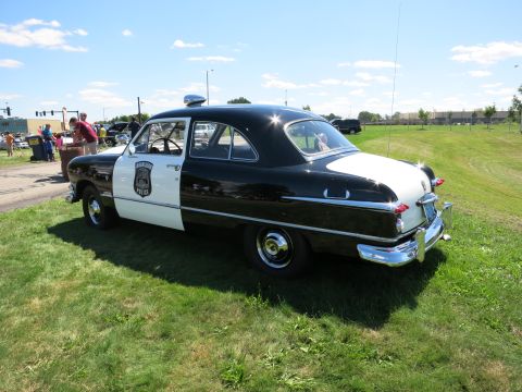 2001 Ford Crown Victoria - A classic black and white police car is displayed outdoors on a sunny day.