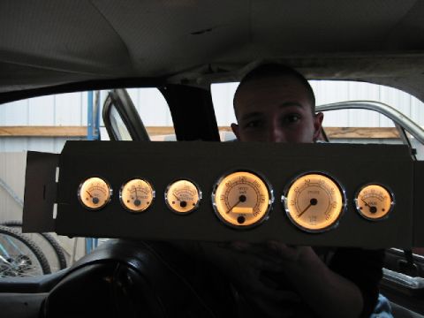 1970 Ford Falcon - Custom gauge cluster with multiple gauges is being held up inside a vehicle.