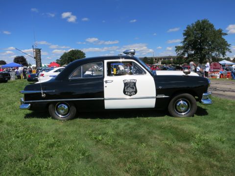 2001 Ford Crown Victoria - A vintage black and white police car is displayed outdoors on a sunny day.