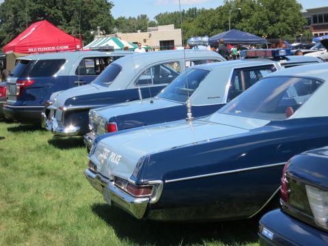 2001 Ford Crown Victoria - A lineup of police vehicles, both modern and vintage models, on display outdoors.
