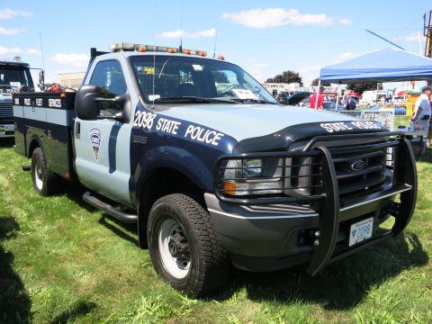 2001 Ford Crown Victoria - A State Police Ford F-Series truck is parked on a grassy field with other vehicles and tents in the background.