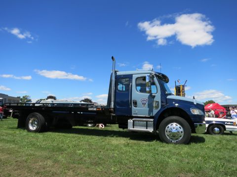 2001 Ford Crown Victoria - Flatbed tow truck with a police car visible in the background under a blue sky.