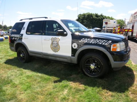 2001 Ford Crown Victoria - A police SUV, marked "Springfield" and "Emergency 9-1-1", is parked on a grassy area.