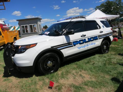 2001 Ford Crown Victoria - A white police SUV with markings for Springfield College is parked on grass under a blue sky.