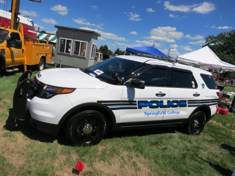 2001 Ford Crown Victoria - A white police SUV is parked on grass with tents and a building in the background.