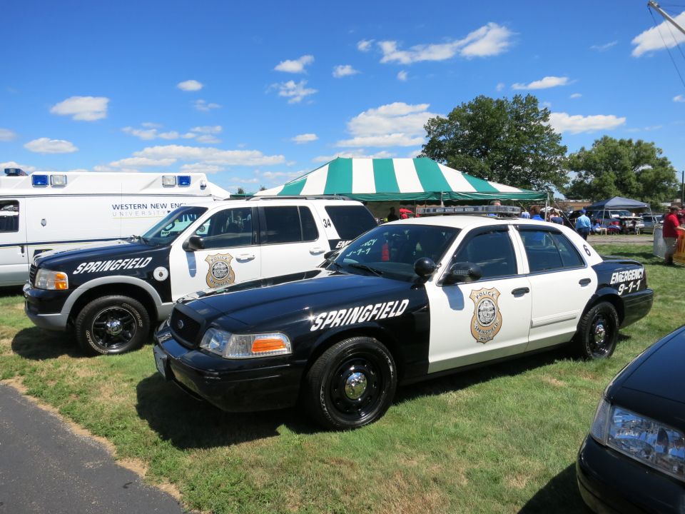 Two police cars, one a sedan and the other an SUV, parked on grass