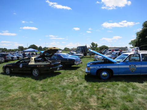 2001 Ford Crown Victoria - A blue and white police car is parked on a grassy field with its hood open, displaying the word "POLICE" on the side.