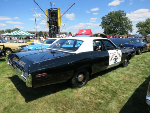 2001 Ford Crown Victoria - A black and white highway patrol car is parked on the grass at an outdoor event, with other vehicles visible in the background.