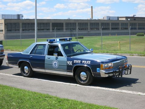 2001 Ford Crown Victoria - Massachusetts State Police car, likely a Ford Crown Victoria, parked on the side of the road.
