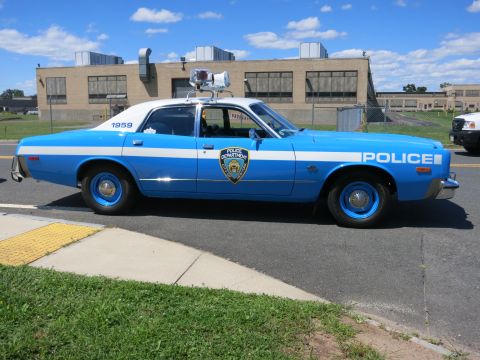 2001 Ford Crown Victoria - A vintage police car with a light bar on the roof is parked on the side of the road.