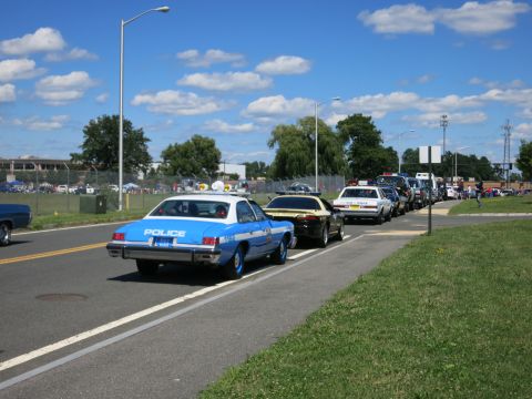 2001 Ford Crown Victoria - A line of police cars, including a vintage model, are parked on a sunny day.