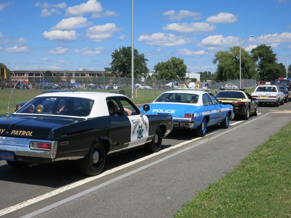 Line of police cars, black and white and blue and white, on a road