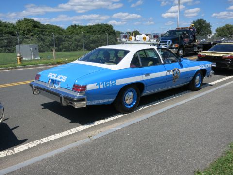 2001 Ford Crown Victoria - A blue and white police car is parked on the side of the road, with a tow truck and another vehicle nearby.