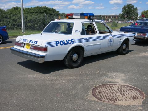 2001 Ford Crown Victoria - A white police car with "POLICE" markings is seen from the side, with another police car partially visible to the right.
