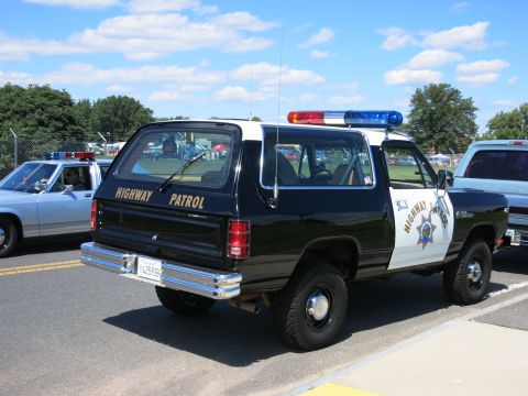 2001 Ford Crown Victoria - A Dodge Ramcharger SUV marked for Highway Patrol is parked next to another police vehicle.