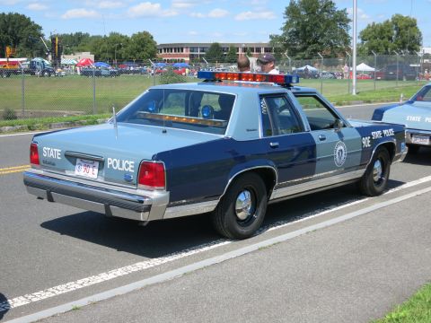2001 Ford Crown Victoria - A two-tone blue and grey state police car is parked on the road with another police car visible behind it.